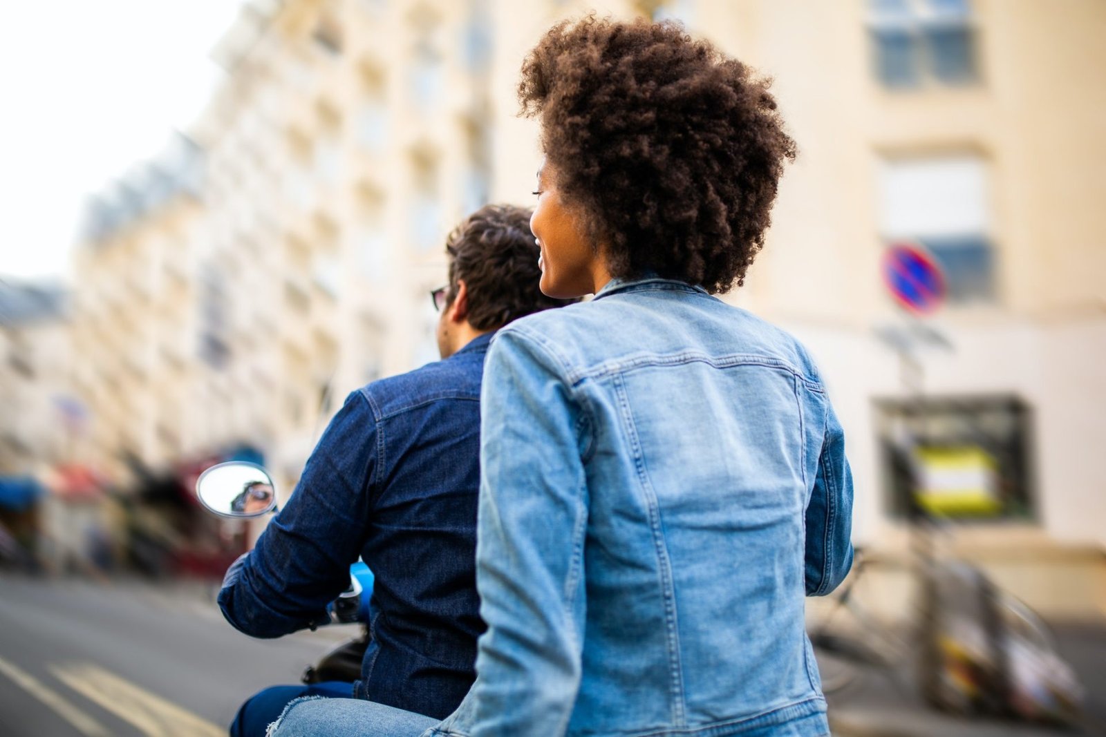 back of African american woman on scooter as passenger