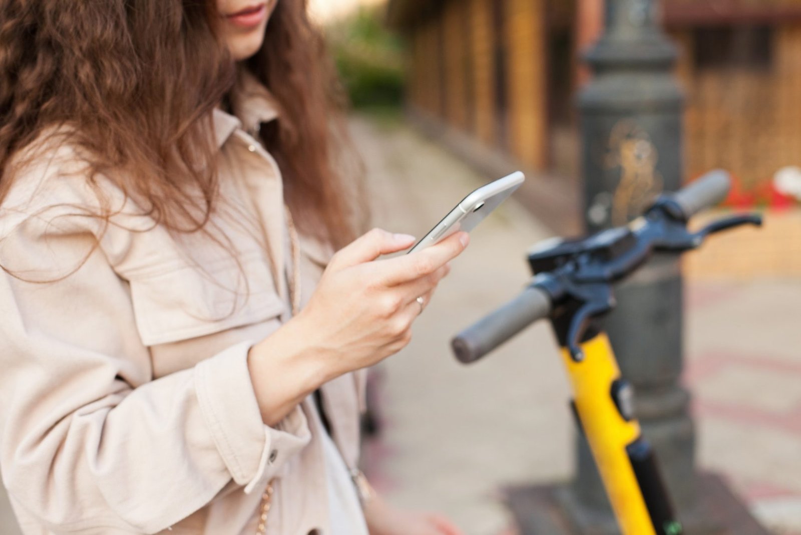 Millennial woman renting a commuting electric scooter on the street, scooter sharing city service