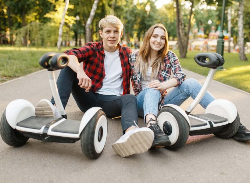 couple-sitting-on-road-with-gyro-board-MSLGQ7C