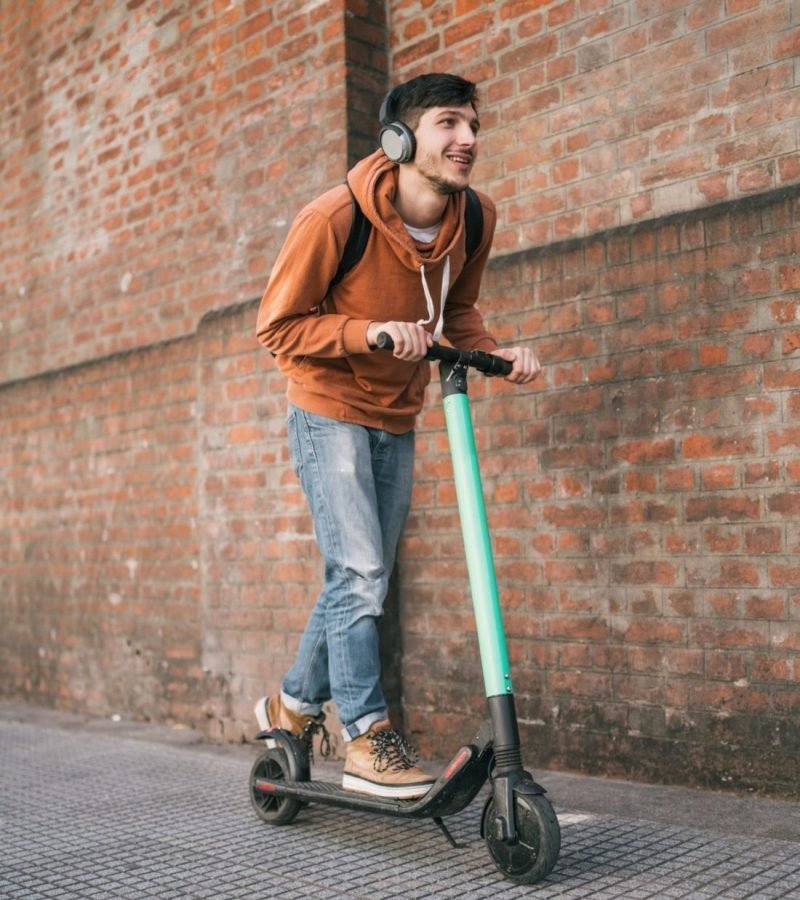 Young man driving electric scooter.